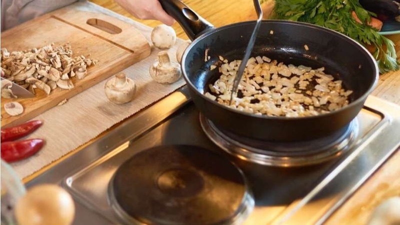 Лук и грибы обжариваются на сковороде