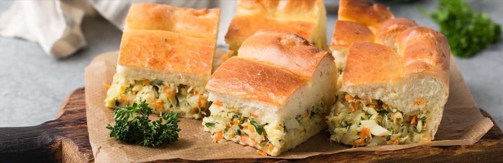 Пирог с рыбной начинкой, овощами и зеленью, разрезанный на порции